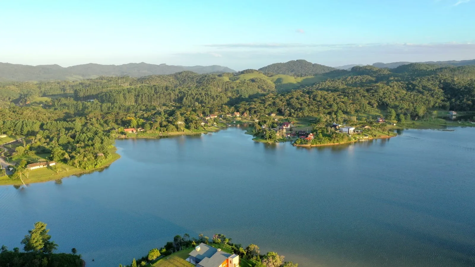 Vista do lago com vilas e montanhas ao amanhecer, em Rio dos Cedros